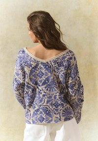 Strickpullover mit lockerem Schnitt, versehen mit einem blauen und cremefarbenen ornamentalen Muster, weitem Ausschnitt und langen Ärmeln. Strukturierter Stoff.