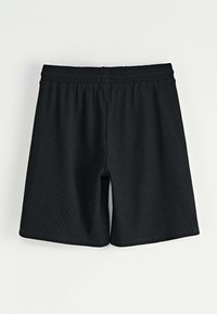 Shorts noirs côtelés avec une taille élastique, présentant une coupe droite et une longueur au genou, fabriqués à partir d'un tissu texturé.