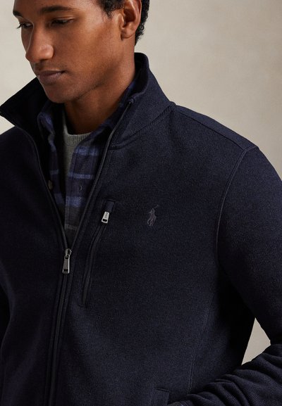 Námořnická bunda na zip s stojáčkem, která má kapsu na hrudi a nenápadné logo. Vyrobena z texturované látky s kontrastními rukávy.