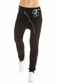 Black jogger pants with a gathered waistband, side zip pocket, and adjustable drawstring. Paired with white sneakers for contrast.
