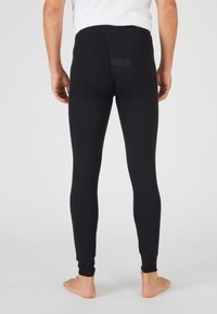 Leggings negras de tela elástica, con una cintura alta, ajuste ceñido y puños de tobillo acanalados. La vista trasera muestra un diseño minimalista.