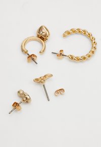 Gouden oorbellen collectie met twee paar creolen, waarvan één gedraaid, en twee studs met decoratieve details en een vlinderslot.