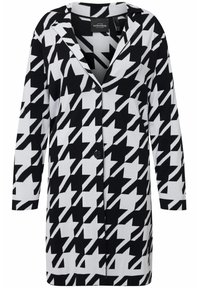 Zwart-wit houndstooth-patroon cardigan met lange mouwen, een gekarteld kraag en twee zwarte knopen aan de voorkant voor sluiting.