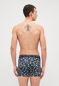 Pánské boxerky, námořnické modré s květinovým vzorem v bílé a zelené. Elastický pás s logem. Hladká látka, přiléhavý design. Výrazné tetování na zádech.