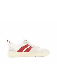 Baskets blanches avec des accents en daim rouge, présentant un design basse-tige, une semelle texturée, un système de laçage et un logo au talon.