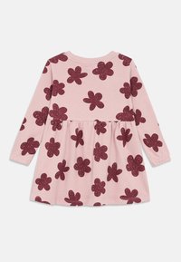 Ροζ φόρεμα με μακρύ μανίκι και μαζεμένη μέση, διακοσμημένο με μωβ λεκιασμένα λουλούδια. Κατασκευασμένο από μαλακό, ελαφρύ ύφασμα.