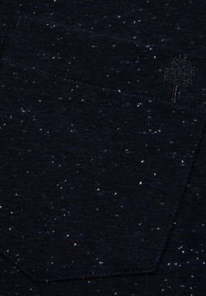 T-shirt bleu marine avec une texture mouchetée, fabriqué en tissu doux. Comprend un petit logo brodé d'arbre sur la poche de poitrine.