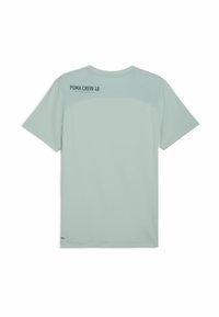 Jasnozielona koszulka z krótkim rękawem, z siateczkowym górnym tyłem i czarnym napisem "PUMA CREW '48" na górze po lewej stronie tyłu.