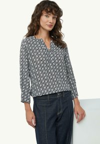 Langärmlige Bluse in Marineblau und Weiß mit einem geometrischen Muster. Der Stoff ist leicht und hat eine weiche Textur sowie einen Kragen.