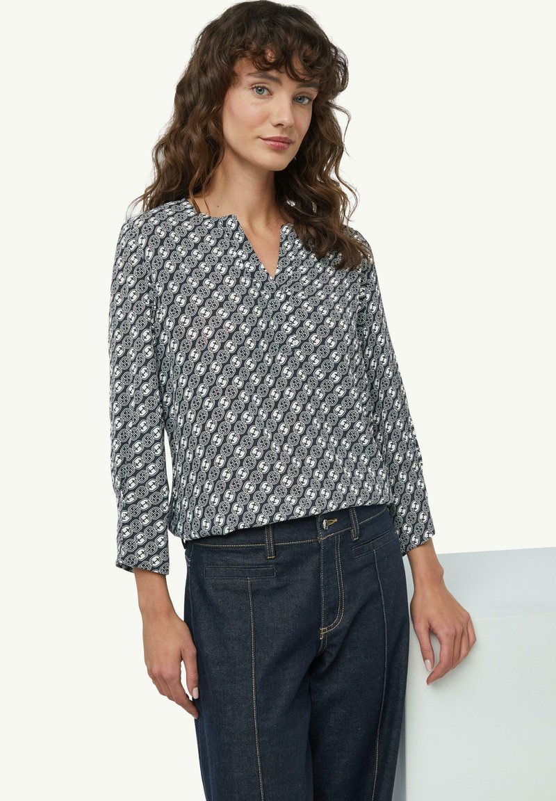 Langärmlige Bluse in Marineblau und Weiß mit einem geometrischen Muster. Der Stoff ist leicht und hat eine weiche Textur sowie einen Kragen.