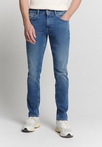 Blauwe denim broek met een rechte pasvorm, voorzien van een knoopsluiting, vijf zakken en subtiele vervaging. Draag je met witte en grijze sneakers.