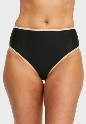 Vrouw draagt zwarte hooggetailleerde onderbroek met beige randje, getoond van taille tot boven de dijen tegen een effen lichte achtergrond.