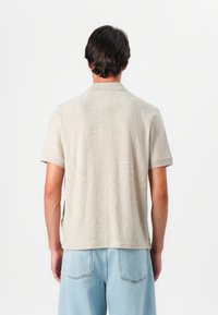 Μπλε πουκάμισο με κοντό μανίκι σε μπεζ απόχρ�ωση με υφή φύλλου, διαθέτει κλασικό γιακά και ευθεία κωνία, φοριέται με ανοιχτού μπλε τζιν.