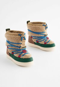 Bottes brunes et vertes avec une tige en beige duveteux, des lacets bleus et un détail de visage souriant. Semelle en caoutchouc, hauteur mi-mollet et col rembourré.