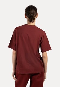 Burgundy bomull t-shirt med korta ärmar, rund hals och avslappnad passform. Slät textur utan synliga mönster eller detaljer.