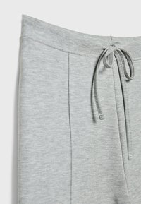 Grå bomulds sweatpants med snoretræk i taljen, der har to lodrette syninger foran og et blødt, tekstureret stof.