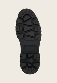 Suola di scarpa in gomma nera con profondi motivi di battistrada e logo "Tom Tailor" sul tallone, progettata per grip e durata.
