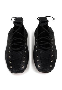 Chaussures en cuir noir avec un design à lacets et des œillets dorés, bout rond et cheville rembourrée. Texture lisse avec un style minimaliste.