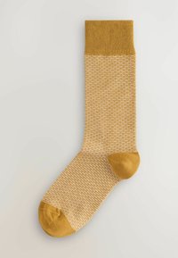 Calcetines amarillos con un patrón texturizado y acentos de color sólido en el puño, el talón y la punta. Tela de punto, longitud hasta la mitad de la pantorrilla.