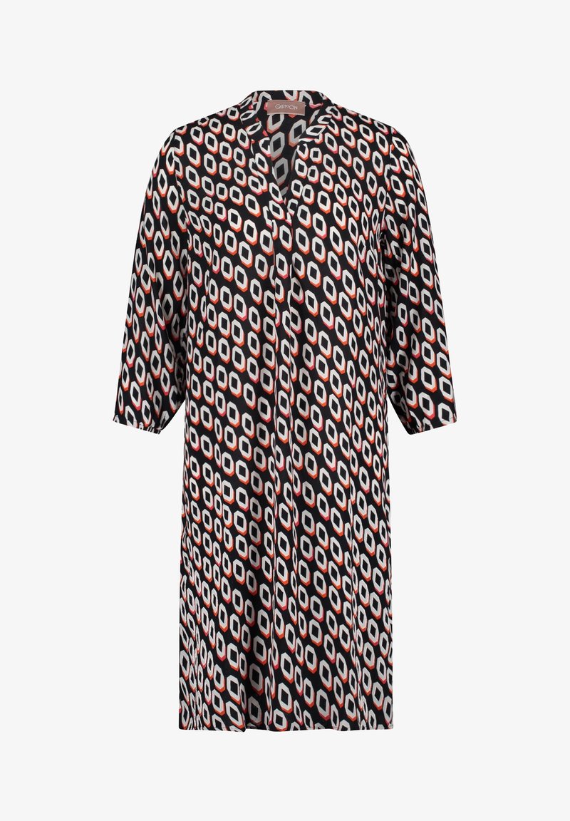 Paino mekko mustalla pohjalla, jossa on geometrinen kuvio valkoisissa, punaisissa ja harmaissa sävyissä. Siinä on lovettu kaulus ja kolmennesosa hihat.