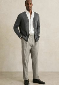 Gray cardigan with buttons, white shirt, gray tailored trousers, and black leather shoes. Smooth fabric, relaxed fit, and neutral colors.