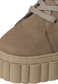 Beige suède platform sneakers, met een gestructureerde zool, ronde neus en platte veters. De bovenkant heeft zichtbare stiksels.