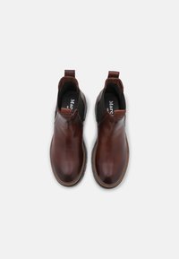 Bruna läderankelbootar med elastiska sidopaneler, rundade tår och dragremmar. Svarta innersulor och kontrasterande sömnadsdetaljer.