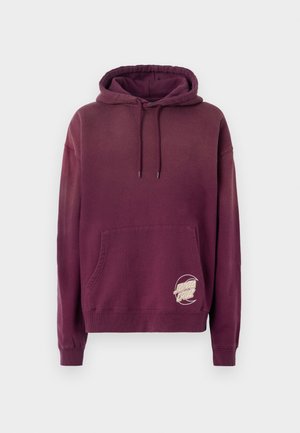 Sweatshirt com capuz em tom bordeaux, possui um bolso frontal, cordões e um logotipo circular branco bordado no canto inferior esquerdo. Textura suave.