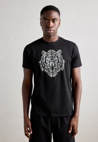 Zwarte katoenen t-shirt met een gedetailleerde witte tijgerafbeelding op de voorkant, korte mouwen en een klassiek ronde hals ontwerp.