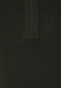 Maglione lavorato a maglia verde scuro con un motivo testurizzato e una cerniera corta sul colletto. Tessuto morbido con un design a vestibilità comoda.