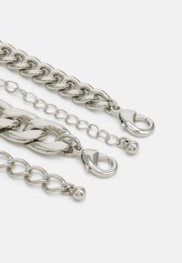 Silver chain accessories featuring varying link sizes, smooth surfaces, and distinct lobster clasps. Includes round bead accents.