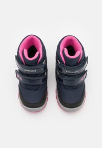 Marinblå stövlar med rosa detaljer, tillverkade av vattentätt material. Innehåller två kardborreband och en texturerad gummisula för bra grepp.