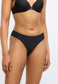 Μαύρο κάτω μέρος μπικίνι από απαλό ύφασμα, με χαμηλή μέση και ελάχιστη κάλυψη, διακοσμημένο με δαντέλα στα πλαϊνά.