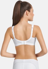 Sujetador deportivo blanco con paneles de malla texturizada, tirantes ajustables y un cierre trasero con gancho y ojal para un ajuste seguro.