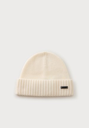 Cream-colored ribbed knit beanie with a folded brim and a small black metal label on the cuff.