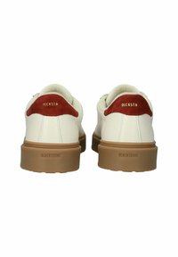 Pair of white sneakers with brown suede heel tabs and gum rubber soles, viewed from the back, featuring "BLACKSTONE" branding on soles and heel tabs.