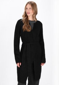 Czarny długi kardigan wykonany z miękkiego, teksturowanego materiału. Charakteryzuje się głębokim dekoltem w kształcie litery V, długimi rękawami oraz paskiem do przewiązania w talii.