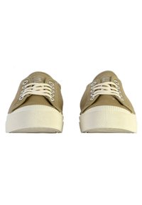Zapatillas de lona beige con cordones blancos, suela de goma y punta texturizada. Presenta ojetes redondos y un logo en la lengüeta.