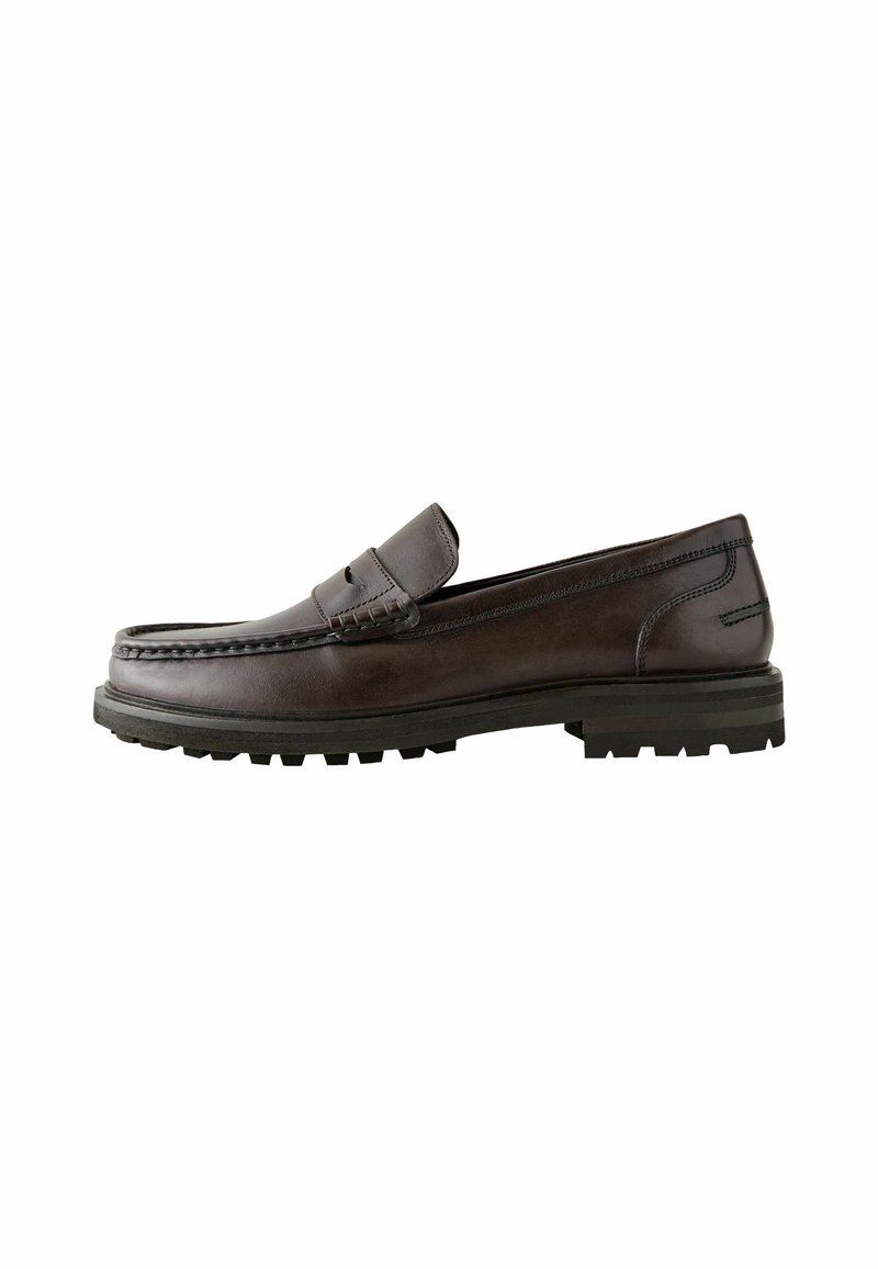 Mocasines de cuero marrón con punta tipo mocasín, costuras detalladas y suela de goma texturizada para mayor agarre. Diseño minimalista y forma clásica.