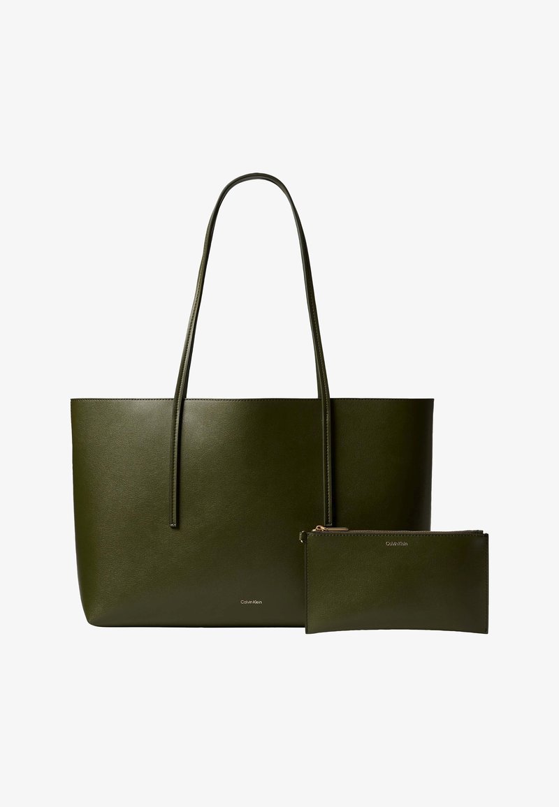 Τσάντα tote από σκούρο πράσινο δέρμα με μακριές λαβές και ένα αντίστοιχο φερμουάρ, και τα δύο με μικρά λογότυπα Calvin Klein.