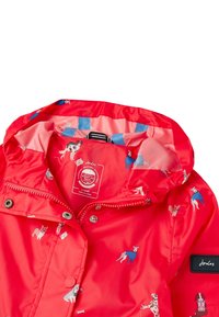 Röd regnjacka med ett mönstrat foder som har hundar. Materialet är glänsande och vattentätt, med huva och dragkedja.