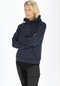 Felpa blu navy con tasca frontale, cappuccio con lacci e logo discreto. Tessuto morbido con vestibilità rilassata e polsini e orlo a coste.