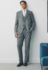Grau kariertes Anzug mit dreifach knöpfbarem Weste, schmal geschnittenen Hosen, weißem Hemd und schwarzen Schuhen. Glatte Textur und klare Linien.