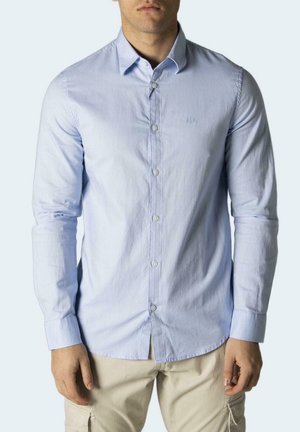 Camisa de botones de manga larga de color azul claro con un corte entallado, que presenta un cuello estándar y un pequeño logotipo en el pecho.