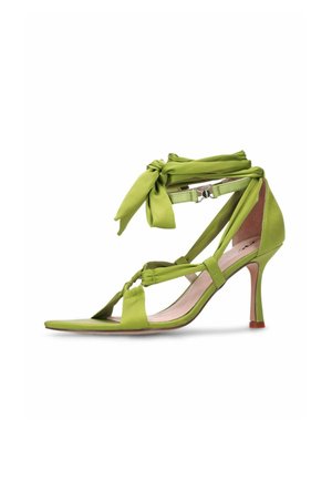 Groene sandaal met hoge hak en enkelriempjes die in een strik zijn gebonden, open teen en smalle hak op een witte achtergrond.