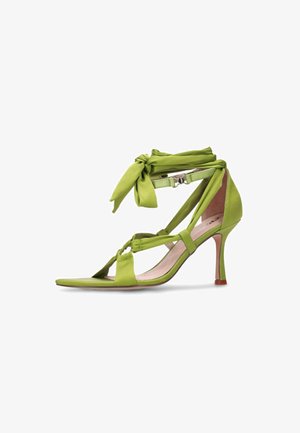 Green high-heeled sandal with ankle wrap straps tied in a bow, open toe, and slim heel on a white background.