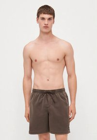 Rudonos spalvos maudymosi šortai su elastinga juosmens juosta, raišteliu ir šoninėmis kišenėmis. Pagaminti iš lygios medžiagos su subtiliu blizgesiu.