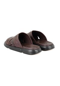 Bruine leren slidesandalen met een gestructureerd oppervlak, uitsnijdingen en een zwarte rubberen zool. Kenmerkt zich door minimale stiksels en een ergonomische vorm.