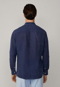 Camicia button-up blu scuro realizzata in un tessuto leggero, con maniche lunghe, colletto e orlo dritto con polsini abbottonati.