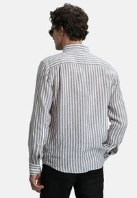 Gestreepte langemouwen shirt in lichtbeige en grijs. Voorzien van een omgevouwen kraag, knoopmanchetten en een gebogen zoom, gemaakt van lichtgewicht stof.
